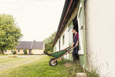 Man with wheelbarrow walking out of barn at farm