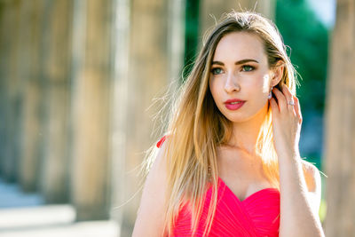 Close-up of beautiful young woman in pink evening dress at colonnade