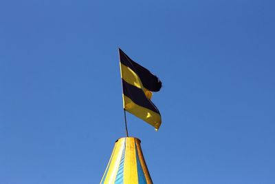 Low angle view of flag against clear blue sky