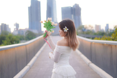 Portrait of young woman standing by railing