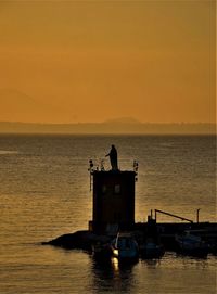 Silhouette boat in sea against sky during sunset