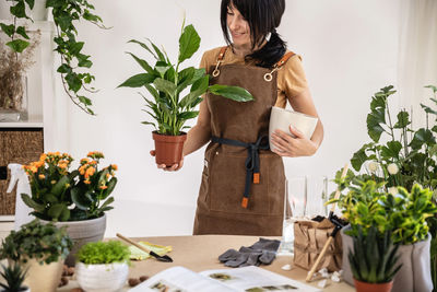 Female gardener holding potted plant, white peace lily