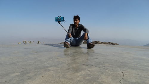 Man taking selfie while sitting against sky