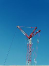 Low angle view of crane against clear blue sky