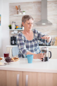 Senior woman making coffee at home