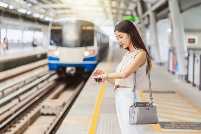 Woman checking time while standing on railroad station