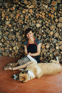 Smiling woman playing with dog at pile of logs at village in portugal