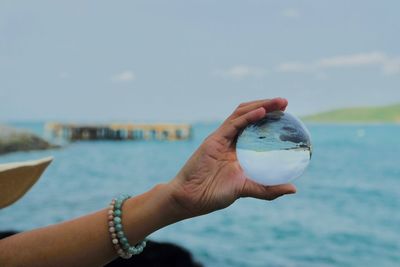 Midsection of person holding sea against sky