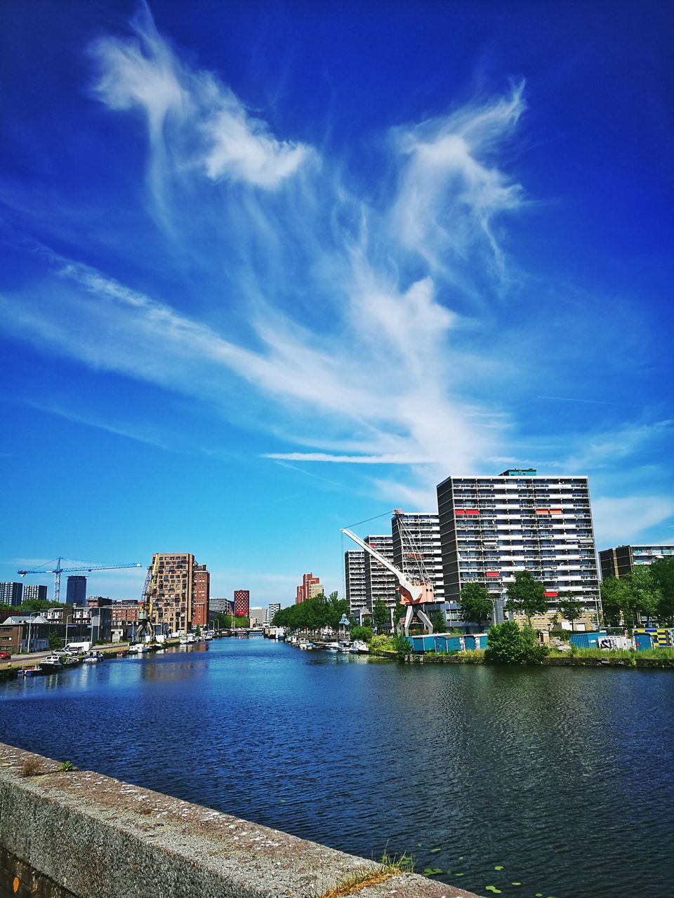 architecture, building exterior, built structure, skyscraper, city, modern, water, sky, city life, waterfront, cityscape, river, cloud - sky, downtown district, urban skyline, residential building, outdoors, day, no people, building story, travel destinations, blue, growth, nature