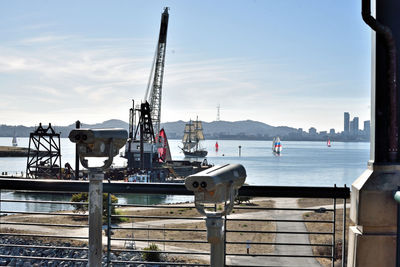 Cranes at harbor against sky