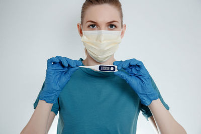 Portrait of young woman holding camera against white background