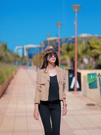 Young woman wearing sunglasses standing against sky