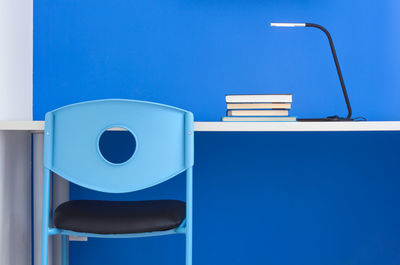 Empty chairs and table against blue wall