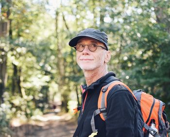 Smiling man wearing cap against trees in forest