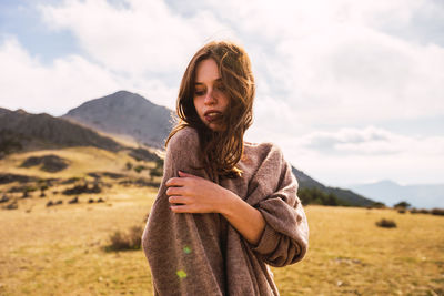 Young woman standing on mountain against sky