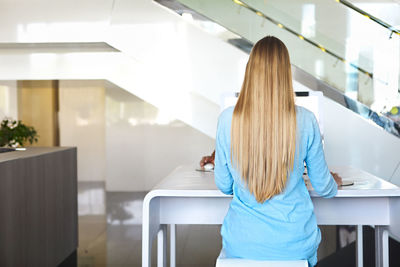 Rear view of woman with blond hair working in office