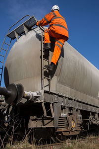 Low angle view of man working against blue sky