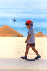 Boy playing on beach against sky