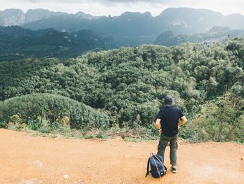 Hiking man with backpack walking in the mountains and taking in the beautiful mountain views.