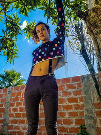 Full length of woman standing against brick wall