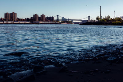 Sea by buildings against sky in city