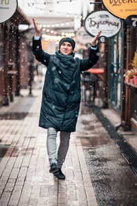 Full length portrait of smiling young woman standing in winter