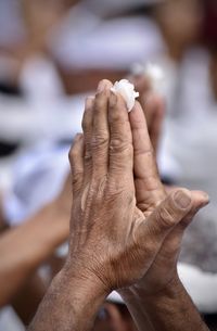 Close-up of hand holding cross against blurred background