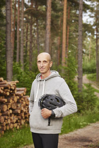 Portrait of man holding bike helmet in forest