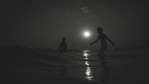 People enjoying on beach against sky at night