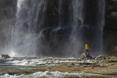 Man standing against scenic waterfall