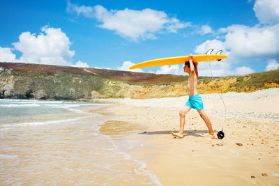 Rear view of woman holding umbrella against sky