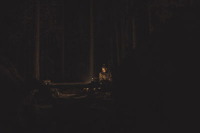 Woman sitting in forest at night