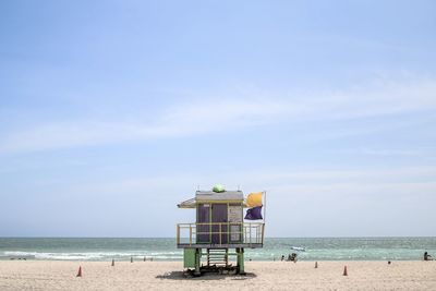 Lifeguard hut on beach against blue sky