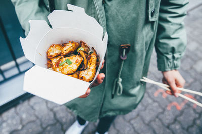 Midsection of person holding street food on sidewalk