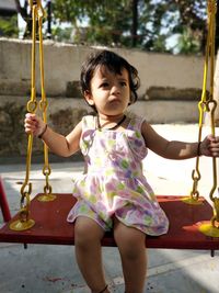 Cute girl sitting on swing at playground