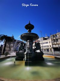 Fountain in city against clear sky