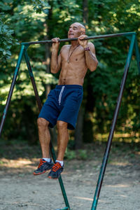 Full length of shirtless man holding umbrella