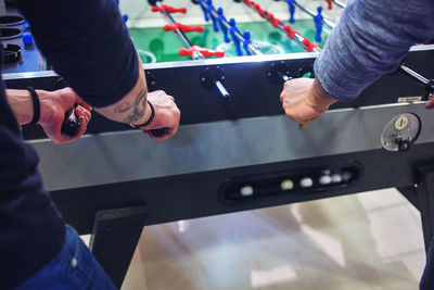 Midsection of friends playing foosball