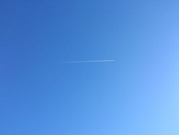 Low angle view of airplane flying in blue sky