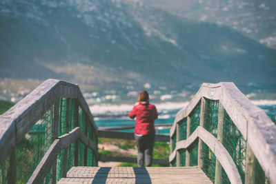 Rear view of woman standing on footbridge