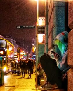 Man sitting in illuminated city at night