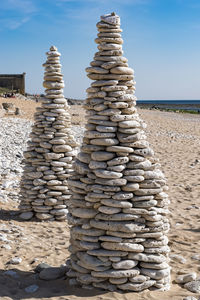 Stack of stones at beach against sky