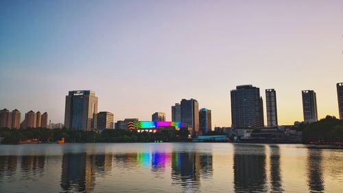 River by buildings against sky during sunset