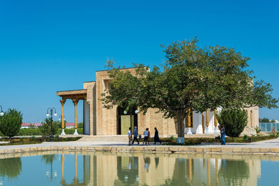 People in front of built structure against clear blue sky