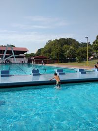 Man swimming in pool against blue sky
