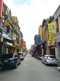 Cars on road in city against sky