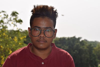 Portrait of young man wearing eyeglasses against sky