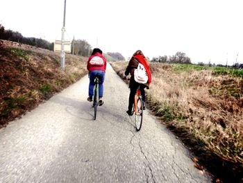 Rear view of person riding bicycle on road