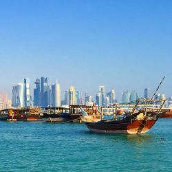 Boats in harbor against clear sky