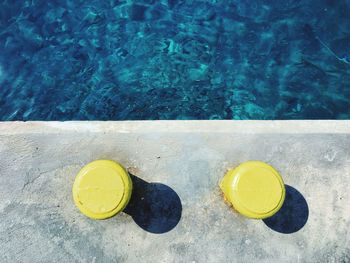 High angle view of yellow bollards by sea during sunny day